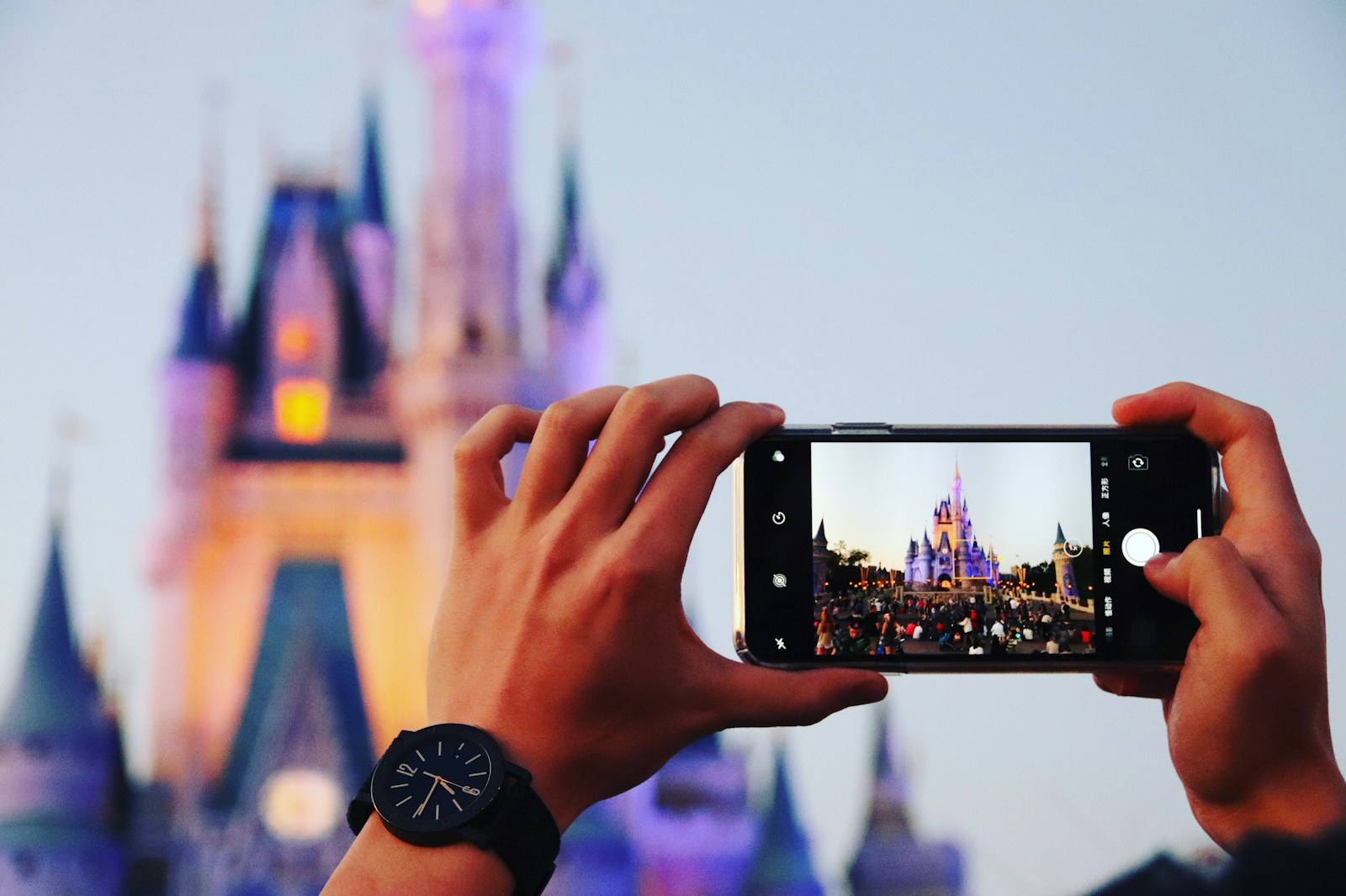 person taking photo a castle using smartphone